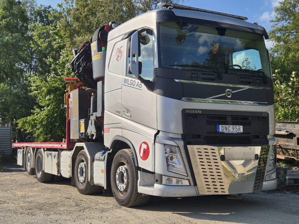 Wilgos Volvo-bodbil med lastflak och hopfälld kran bakom hytten.