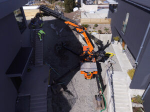 Jekkokran från Wilgo uppställd mellan två hus vid arbete med en betongtrappa, sedd ovanifrån.